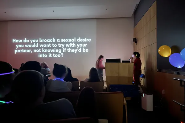 Sex in the Dark education event with lights off and white letters that say how do you broad a sexual desire that you would want to try with your partner, not knowing if they'd be into it too?