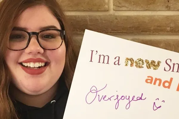 Smiling person holding sign "I'm a new Smithie and I'm overjoyed"