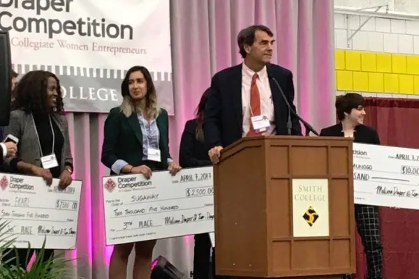 Person at podium with people behind holding large checks