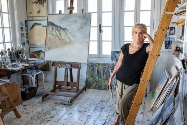 Barefoot Anne Peretz in her studio, surrounded by paintings and easels