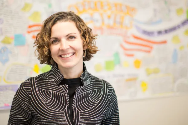 Erin Cohn against a out-of-focus white board covered with writing in bright marker