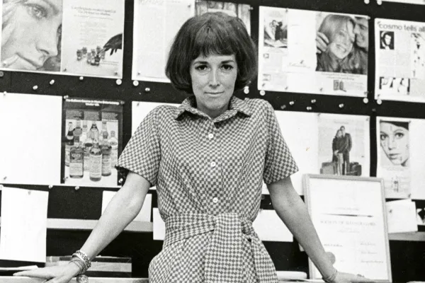 Helen Gurley Brown leaning against desk