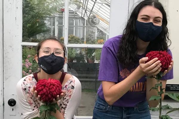 Mai Klooster and Sasha Zeidenberg holding large mum flowers