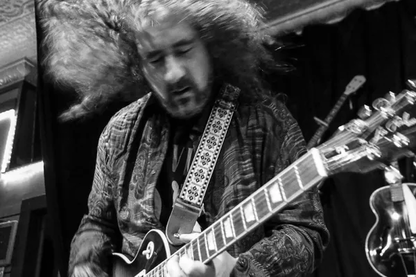 Steve Waksman playing guitar with his long curly hair flying