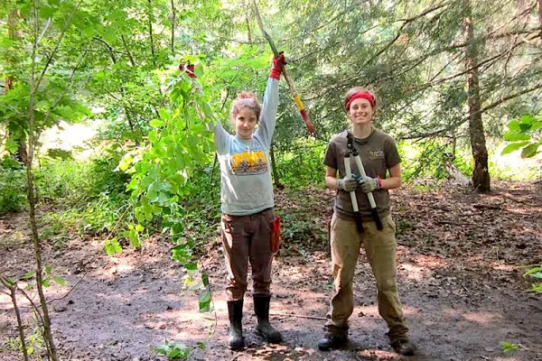 Meg Kirsch '17 (right) and Rebecca Tishler of Mount Holyoke College, help pull invasive plants last summer from the banks of the Mill River on Smith's campus.