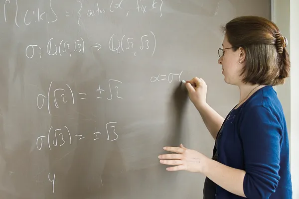 Student working on a math equation at a blackboard