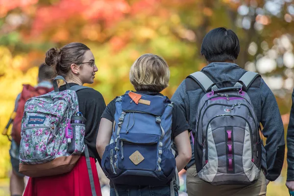 Three students with backpacks walking away from the camera