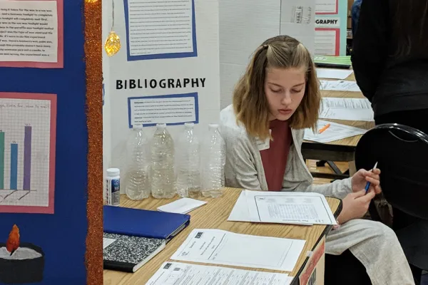 Student studying her notes at her booth during a science fair