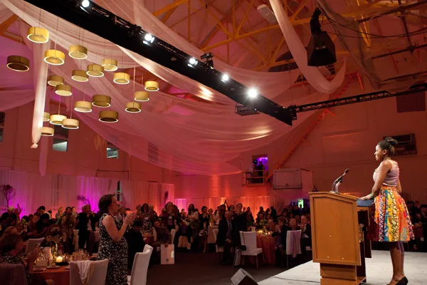 Student at a podium speaks to a dinner gathering