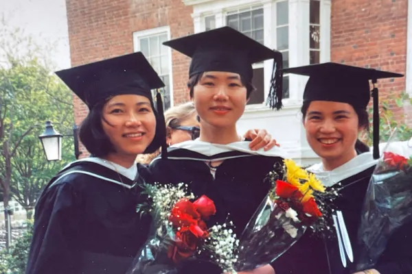 Three students at graduation holding roses