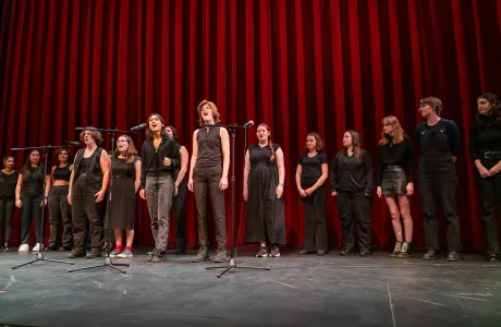 A group of Smith students singing in front of a red curtain