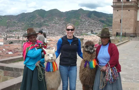 A woman poses with llamas and two Peruvian women
