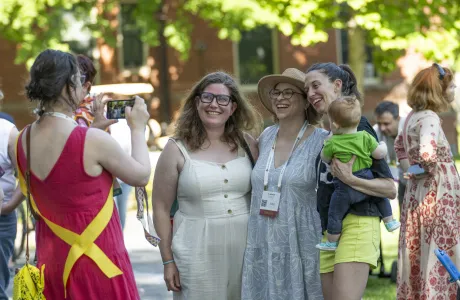 A group of alums pose for a photo during Reunion Weekend. One is balancing a baby on her hip.