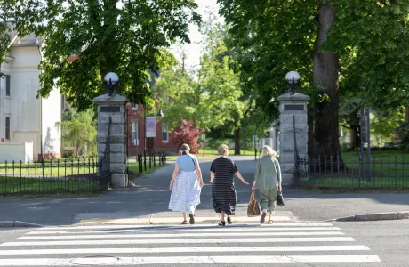 Three alums walking onto campus