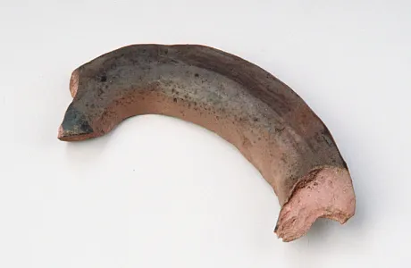 A curved, brown pottery shard with varying textures and a rough, broken edge