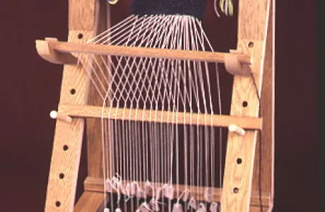 Small wooden loom with strings and fabric being woven