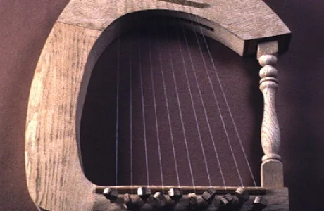 A wooden harp with a curved frame, ten strings, and a crafted arm