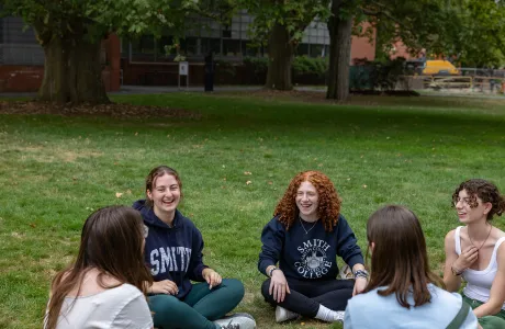 A group of new students sit on the grass and talk