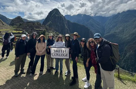 A group of people holding a Smith College banner at Machu Picchu