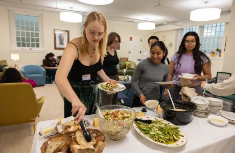 Students mingling and plating food in the Bodman Lounge of the Chapel