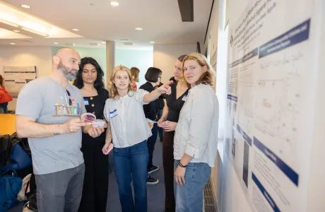 A student explains their poster presentation to a faculty member