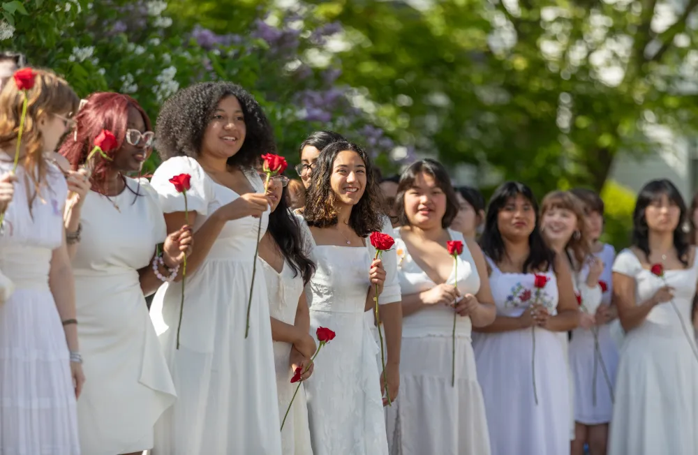 Students wearing white hold roses on Ivy Day