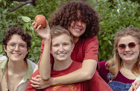 One student giving another a piggy back ride while they hold an apple