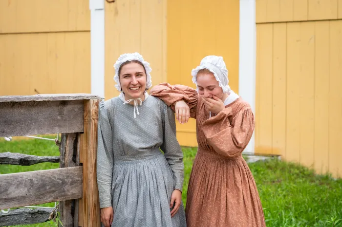 Two students, interns at a historical living museum, dressed in bonnets.