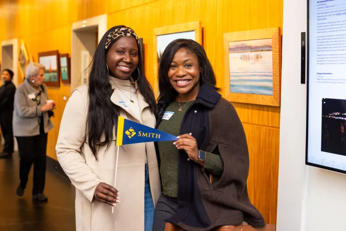 Two alums posing with a Smith College pennant. 