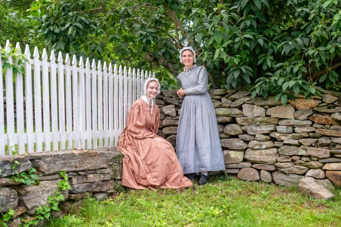 Two students dressed in clothes from the 1830s, interning as costumed interpreters at Old Sturbridge Village.
