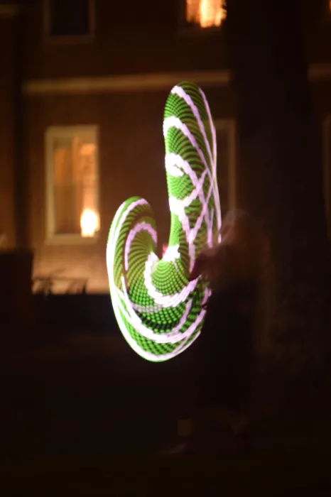 Una Fonte is a blur of green and white color while dancing with LED hula hoops at night