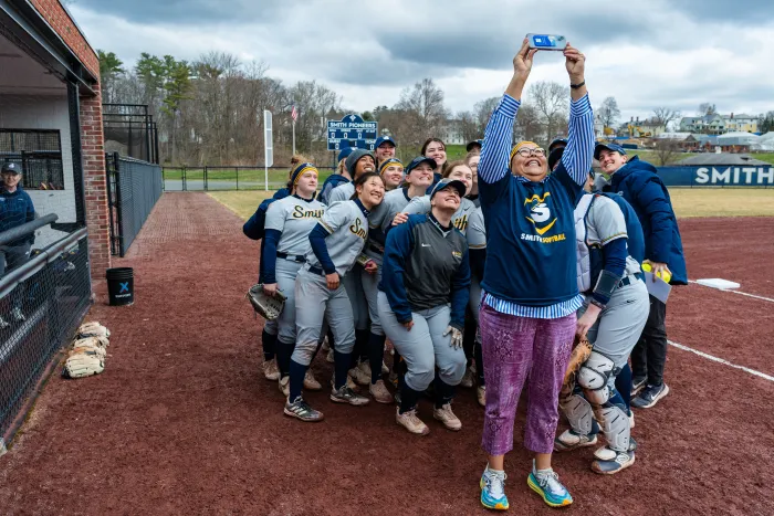 Sarah Willie-LeBreton takes a selfie with the softball team behind her.