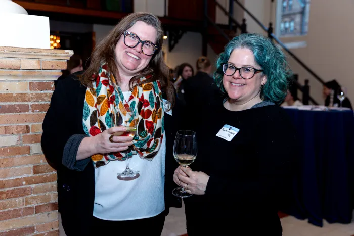 Two alums smile at the camera.