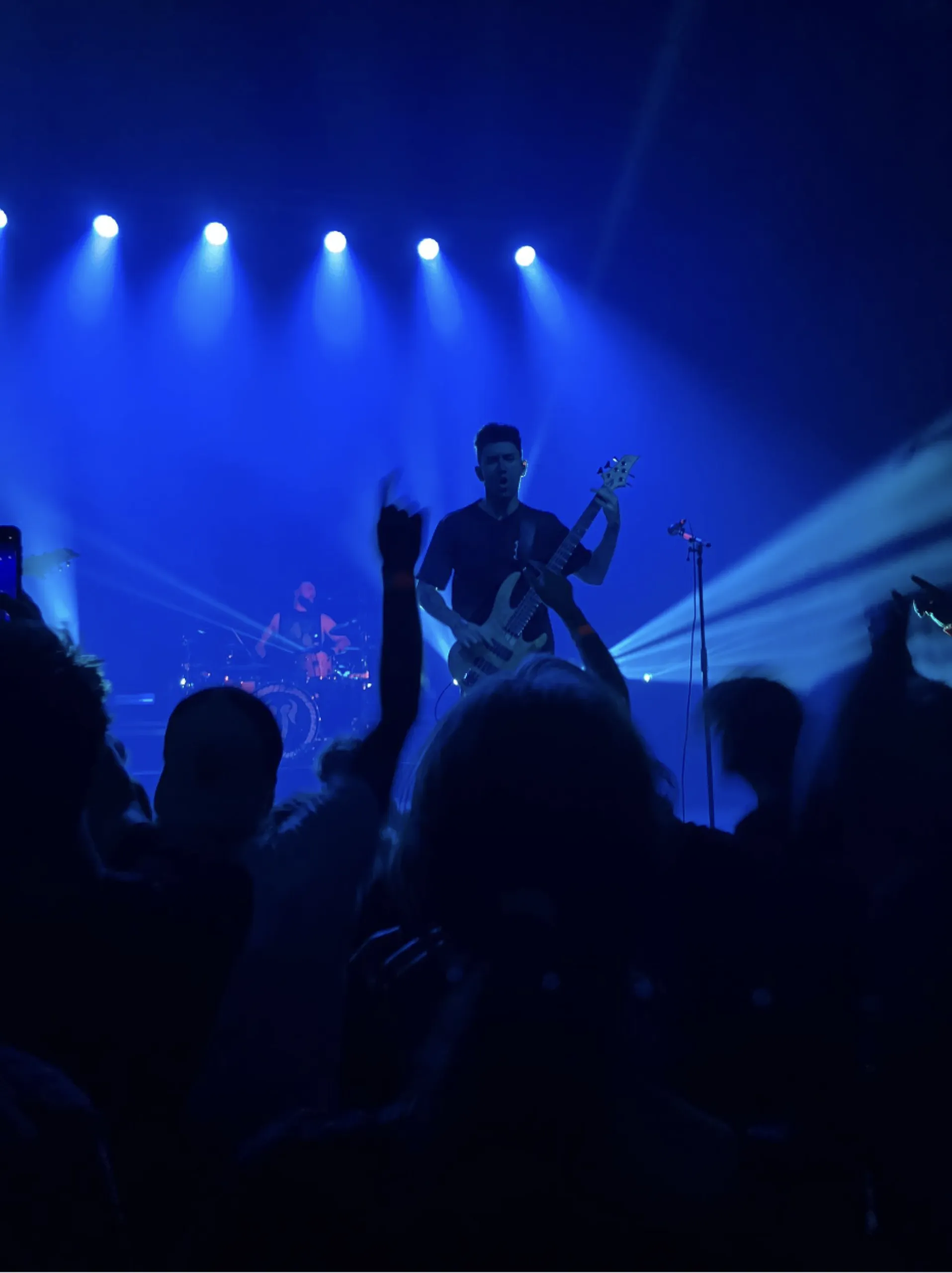 Someone stands on stage with a guitar, and are backlit in blue.