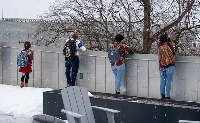 Students standing on the roof of Neilson library, looking over the edge