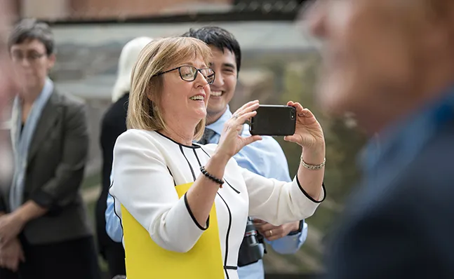 President Kathy McCartney takes a photo at the Neilson groundbreaking