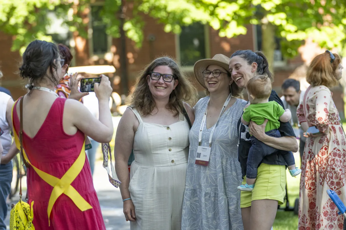 A group of alums pose for a photo during Reunion Weekend. One is balancing a baby on her hip.