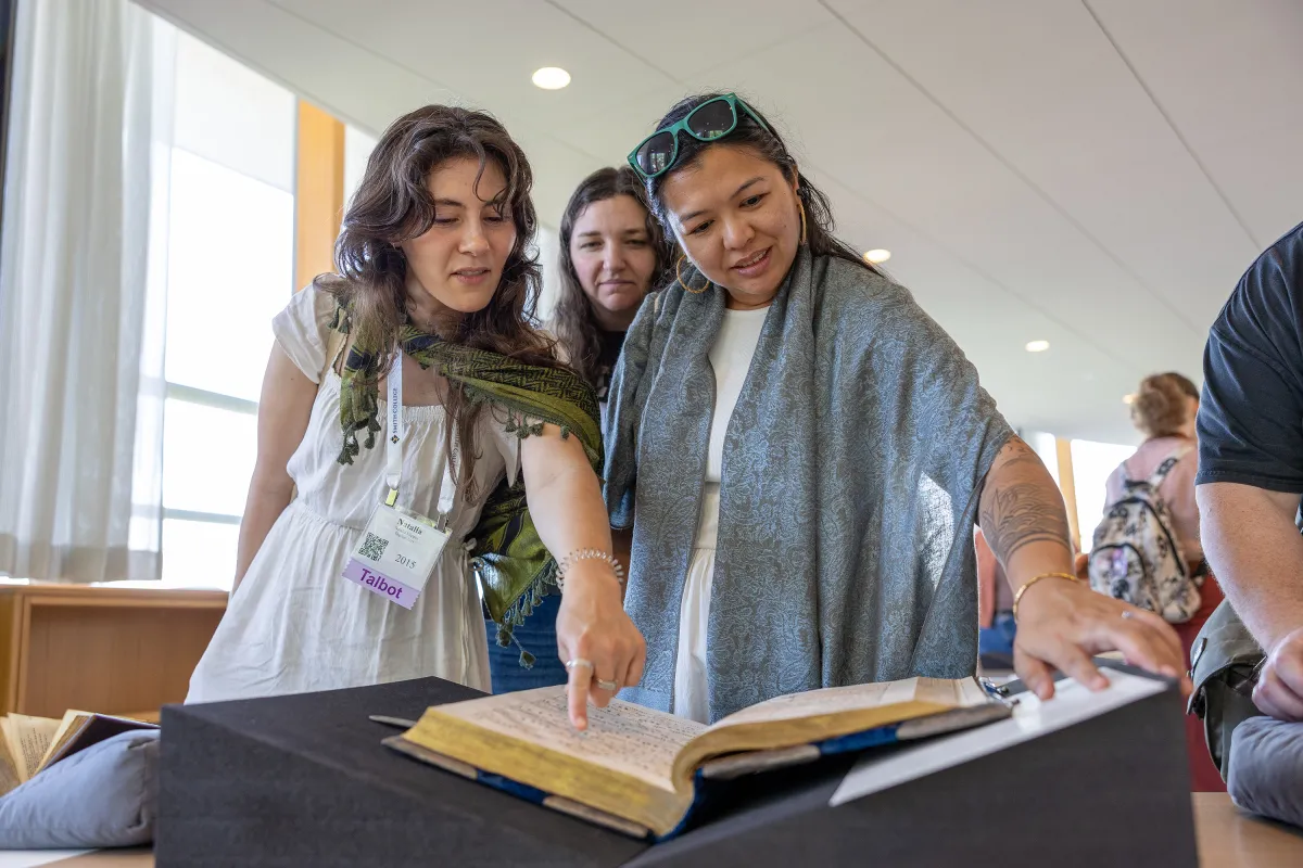 Alums smile and look at a book in Neilson Library during Reunion weekend