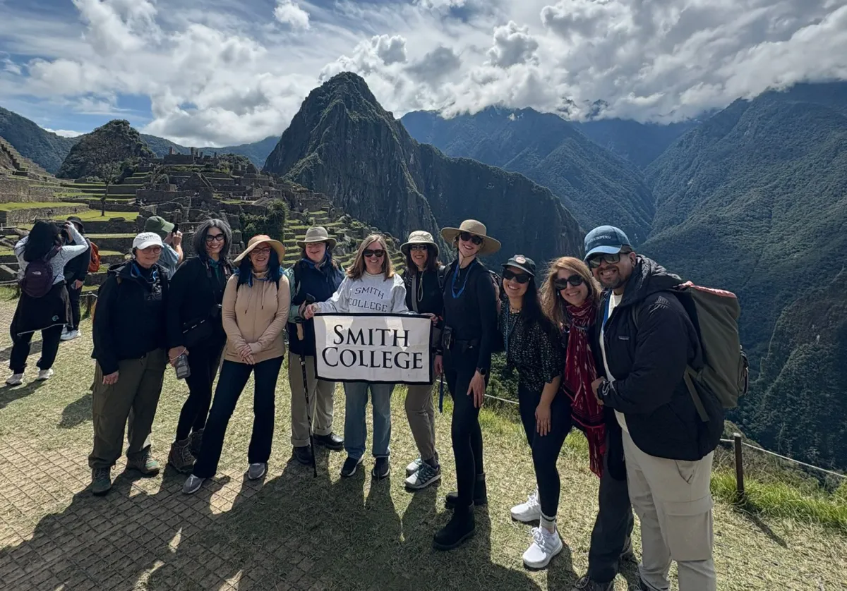 A group of people holding a Smith College banner at Machu Picchu
