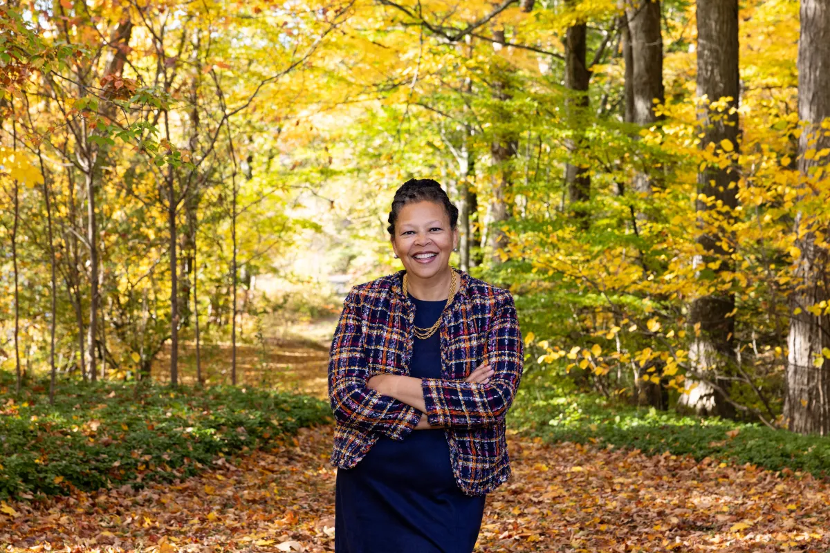Sarah Willie-LeBreton standing in front of trees in the fall
