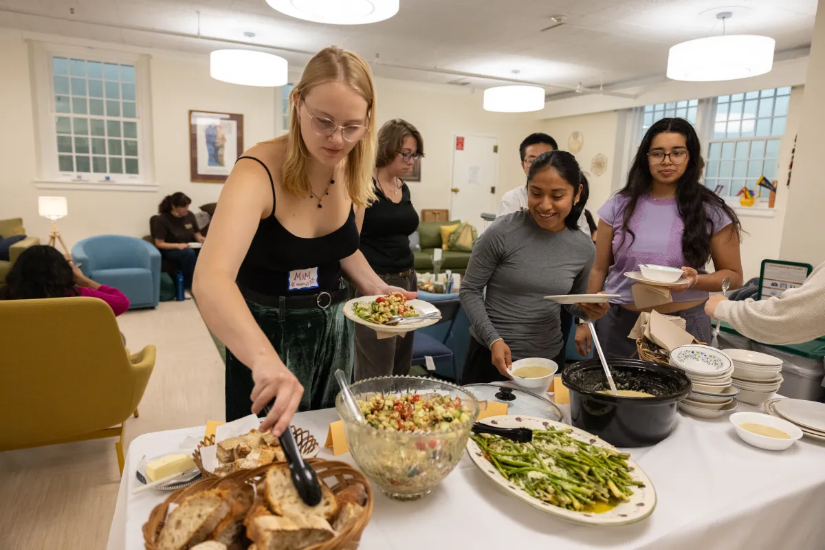 Students mingling and plating food in the Bodman Lounge of the Chapel