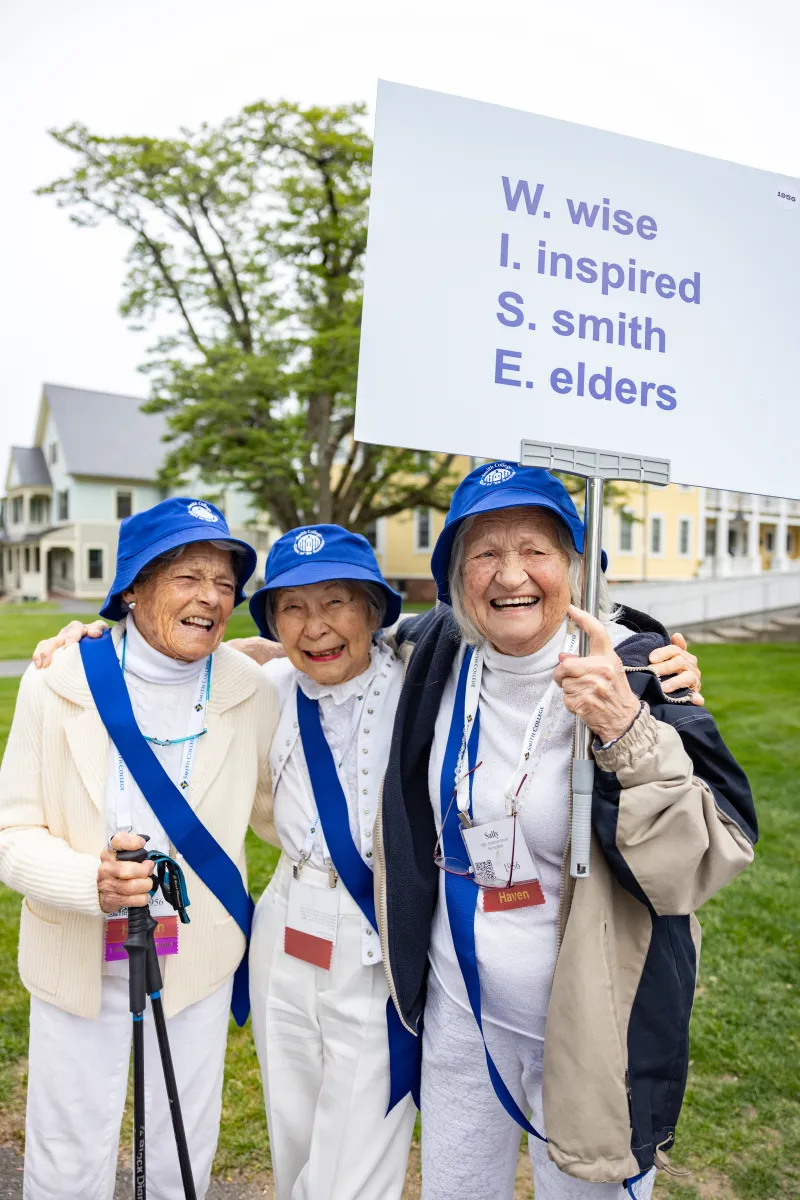 Smithies smile holding a sign that says Wise, Inspired, Smith, Elders