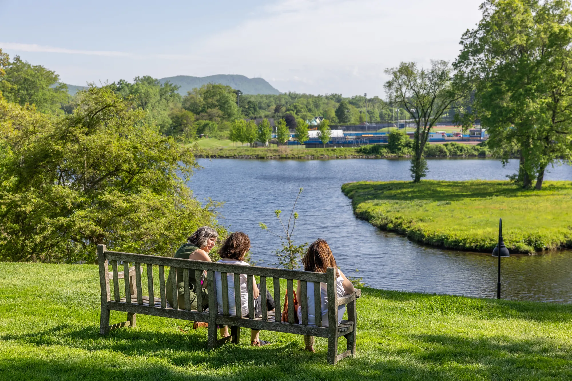 Alums sit on a bench looking out over Paradise Pond