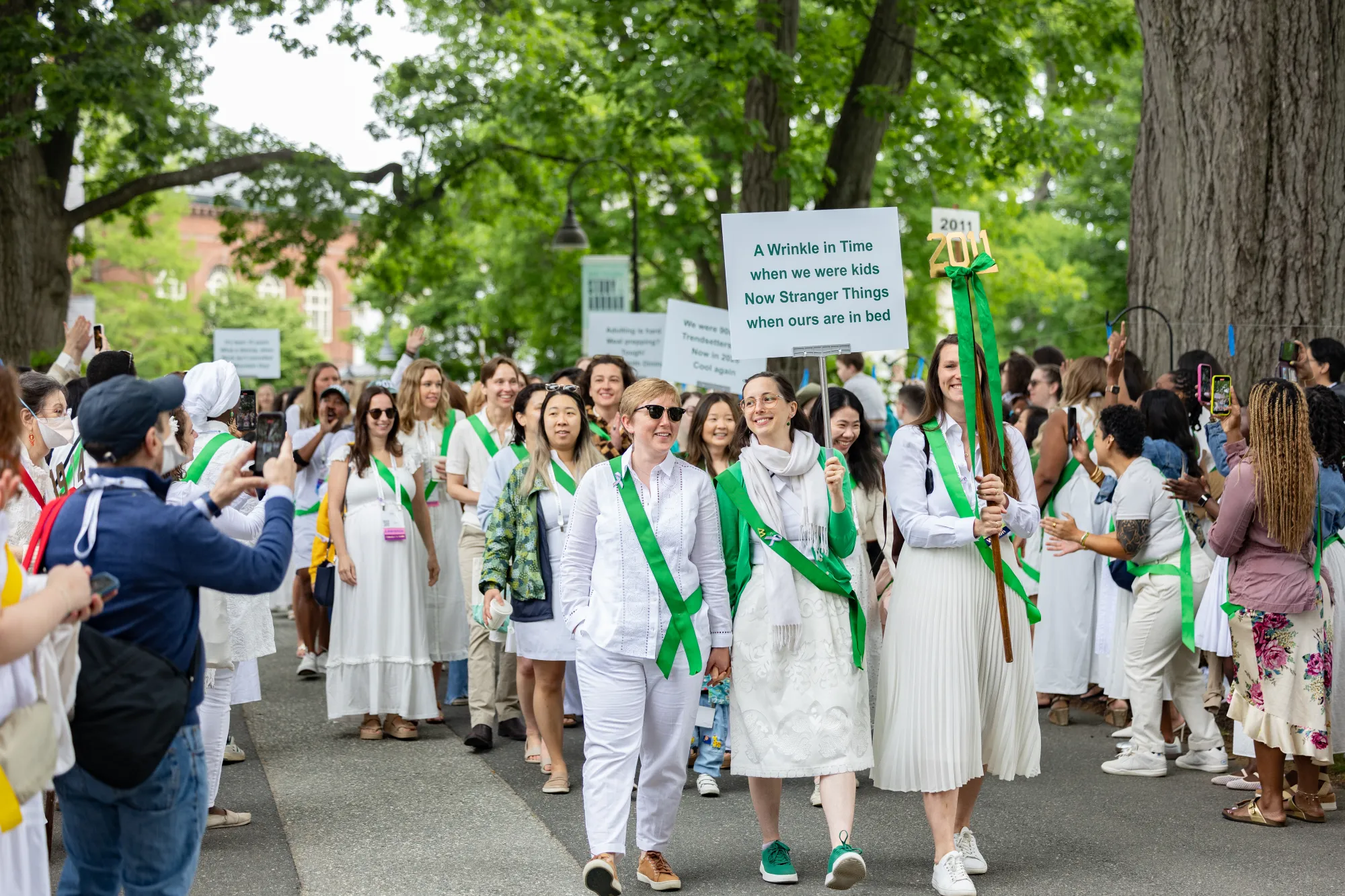 Members of the class of 2011 march carrying signs and wearing green sashes