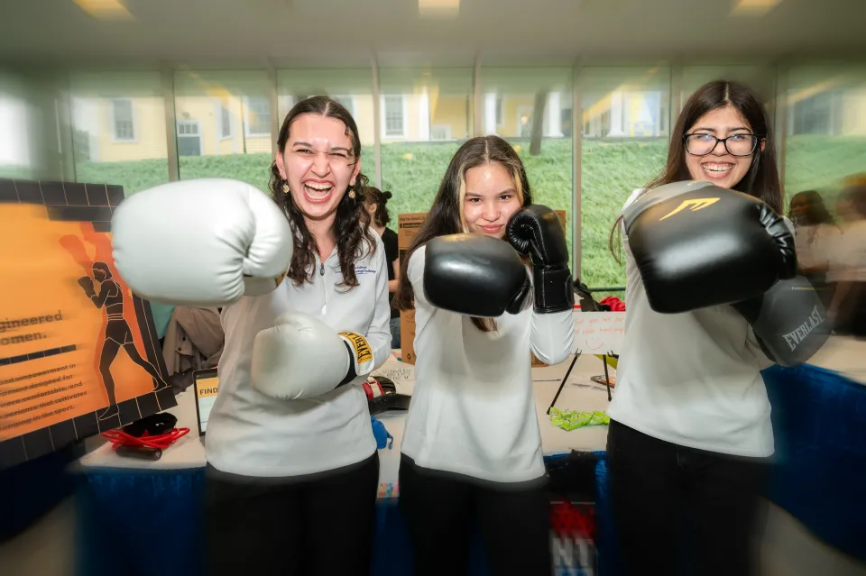 Three students hold up boxing gloves to the camera