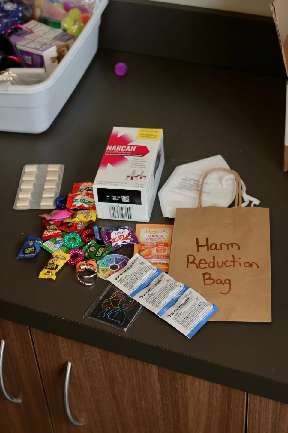 Harm reduction bag and items to fill it including Narcan, candies and fidget toys