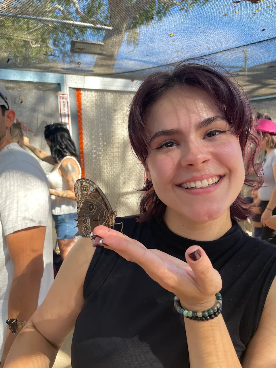 Katherine Booth, smiling, holding a brown butterfly