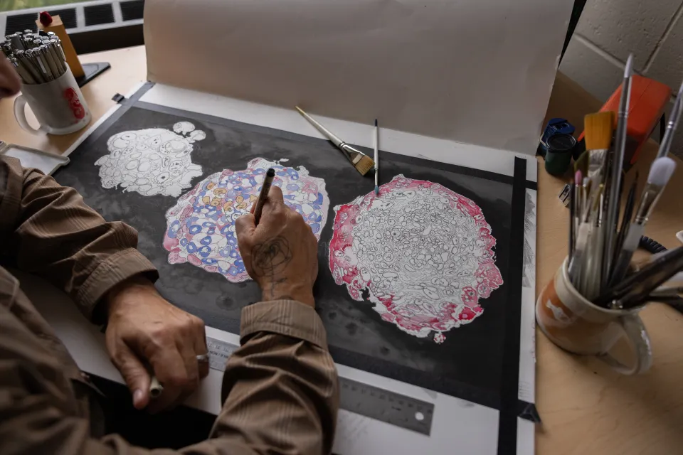 A close up of Michael Barresi working on watercolor paintings of human embryo cells.