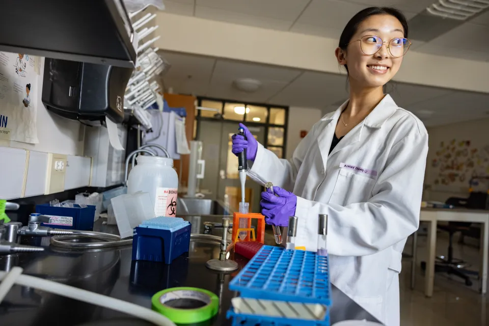 Ashley Cheng in a lab at Smith, holding a pipette and wearing a white lab coat