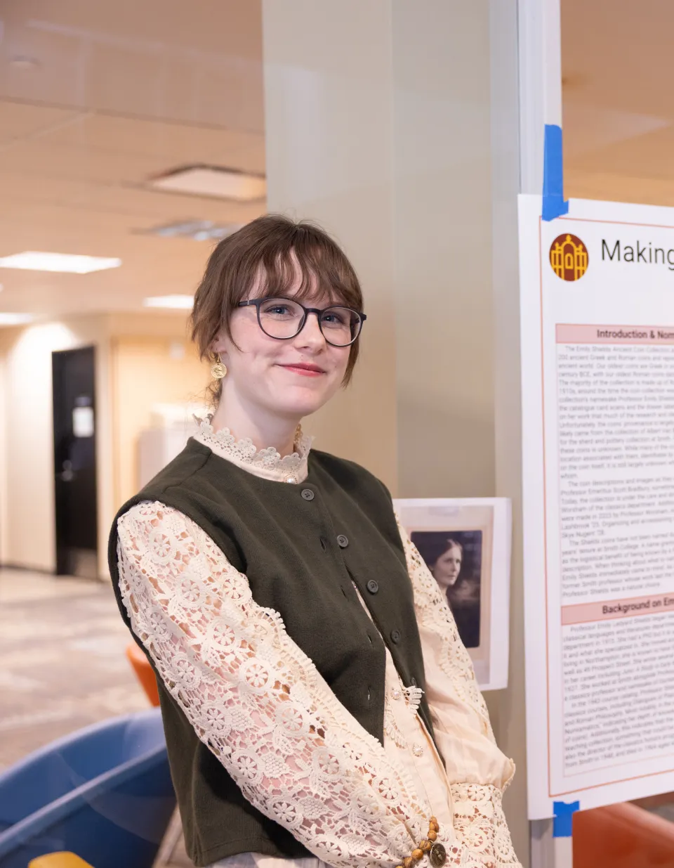 Skye Nugent stands in front of a photo of Emily Shields, whom she named the ancient coin collection after